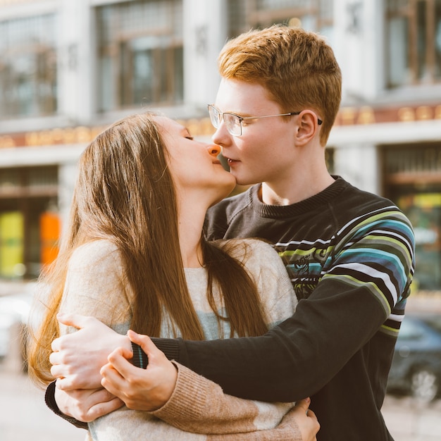 The redhead boy looks tenderly at girl and kiss. Concept of teenage love and first kiss