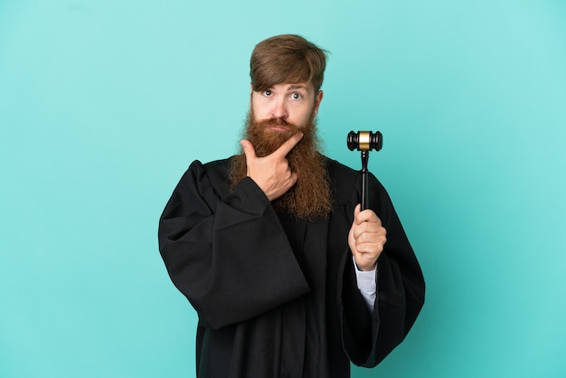 Redhead caucasian judge man isolated on blue background thinking