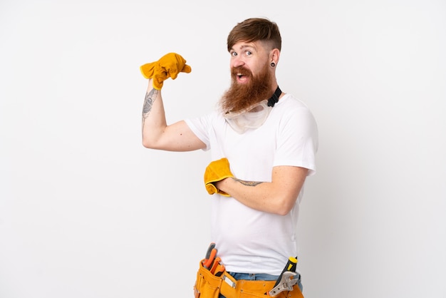 Redhead electrician man with long beard over white wall making strong gesture