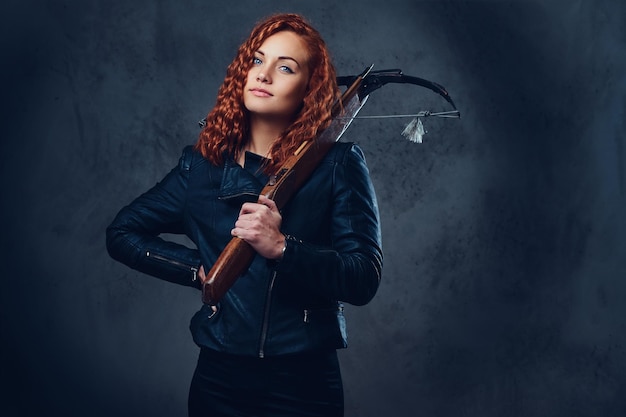 Redhead female dressed in an elegant suit holds crossbow.