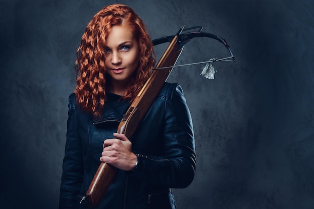 Redhead female dressed in an elegant suit holds crossbow.