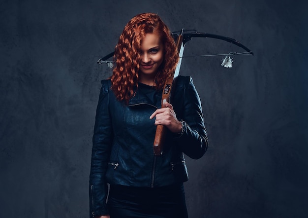 Redhead female dressed in an elegant suit holds crossbow.