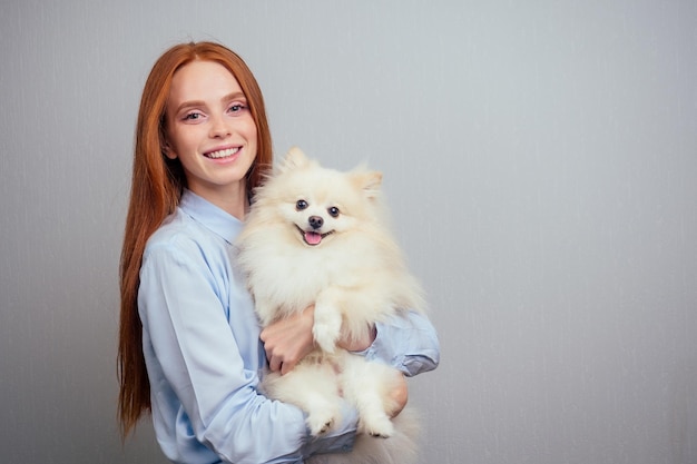 Redhead girl falling in love of her fluffy spitz at home sun light sunset in window background