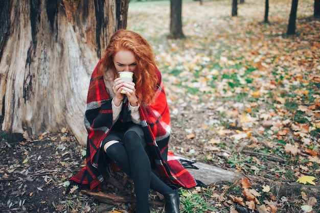 Photo redhead girl holding coffee in autumn park