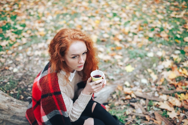 Photo redhead girl holding coffee in autumn park