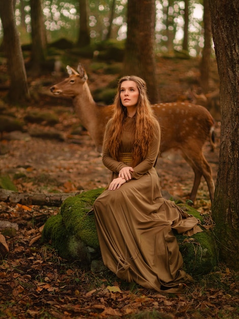 Redhead girl with deer in a long dress