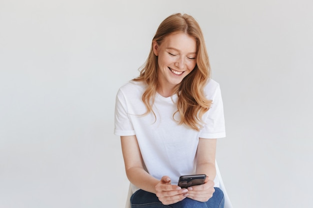 Redhead happy woman using mobile phone.