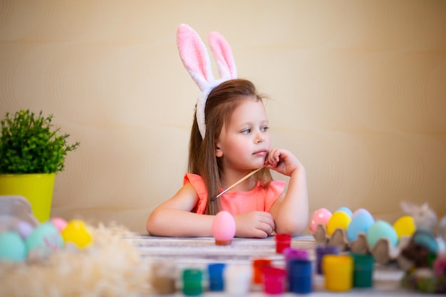 Redhead little girl in bunnies ears prepares for easter painted easter eggs happy easter concept