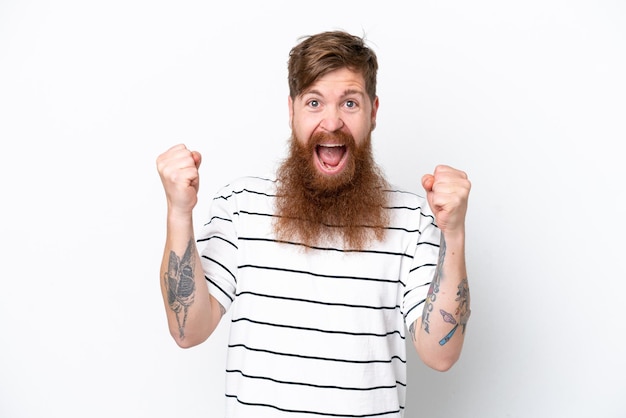 Redhead man with beard isolated on white background celebrating a victory in winner position