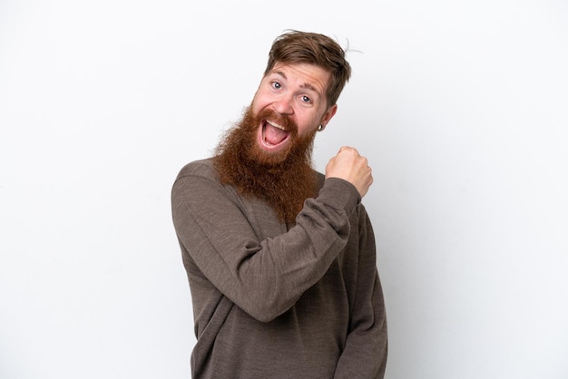 Redhead man with beard isolated on white background celebrating a victory