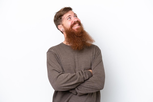 Redhead man with beard isolated on white background looking up while smiling