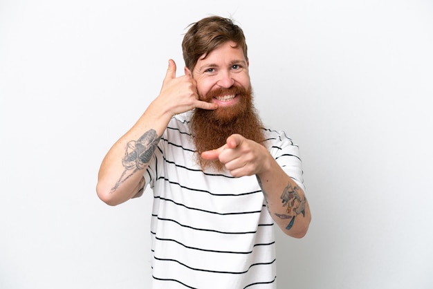 Redhead man with beard isolated on white background making phone gesture and pointing front