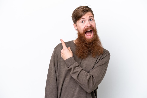 Redhead man with beard isolated on white background surprised and pointing side