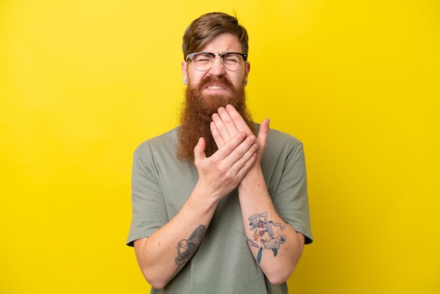 Redhead man with beard isolated on yellow background suffering from pain in hands