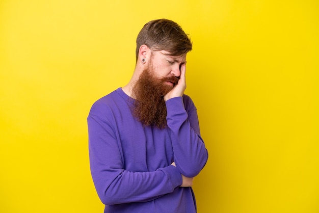 Redhead man with beard isolated on yellow background with headache