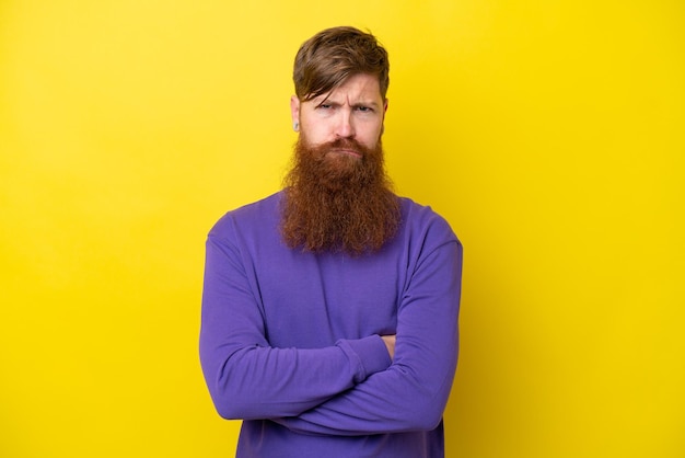 Redhead man with beard isolated on yellow background with unhappy expression