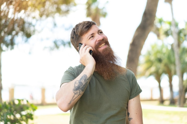 Redhead man with beard keeping a conversation with the mobile phone