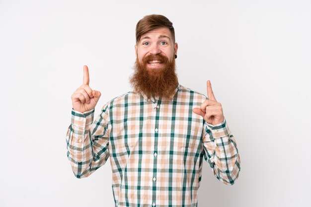 Redhead man with long beard over isolated white wall pointing up a great idea