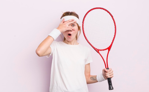 Redhead pretty girl looking shocked scared or terrified covering face with hand tennis concept