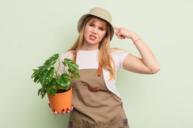 Redhead pretty woman feeling confused and puzzled showing you are insane gardener concept