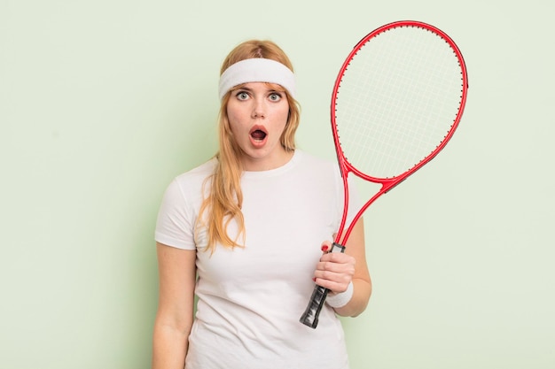 Redhead pretty woman looking very shocked or surprised. tennis concept