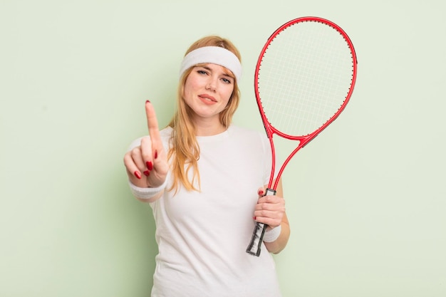 Redhead pretty woman smiling proudly and confidently making number one. tennis concept