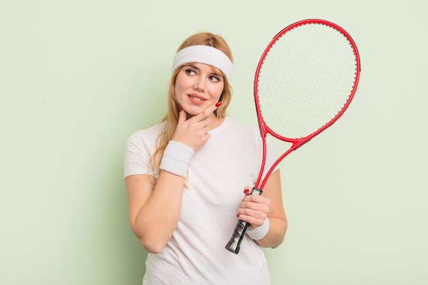 Redhead pretty woman smiling with a happy confident expression with hand on chin tennis concept