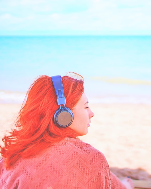 Redhead sexy woman listening to music on the beach amazing woman on break in sunbathes on the coast ...