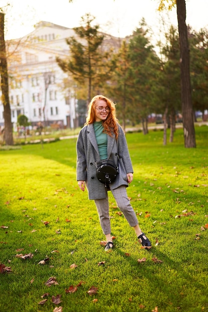 Redhead smiling pretty woman walking in park on sunny autumn day elegant female poses in stylish