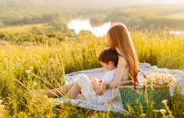 Redhead teen girl embracing little brother at picnic