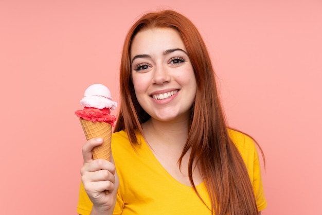 Redhead teenager girl with a cornet ice cream over isolated wall