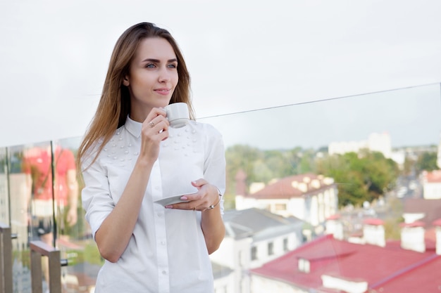 Redhead white woman in white shirt drinking coffee