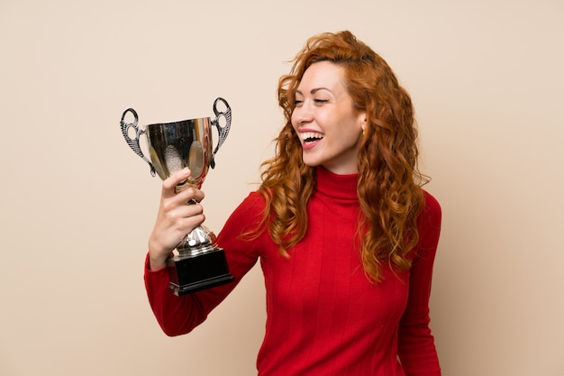 Redhead woman with turtleneck sweater holding a trophy