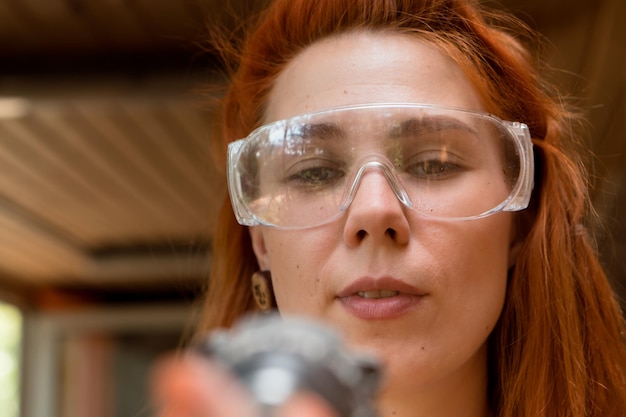 Redhead young woman uses screwdriver working at home