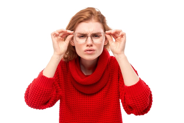 Redhead young woman wearing glasses squinting while looking at camera isolated on white background Vision problems concept