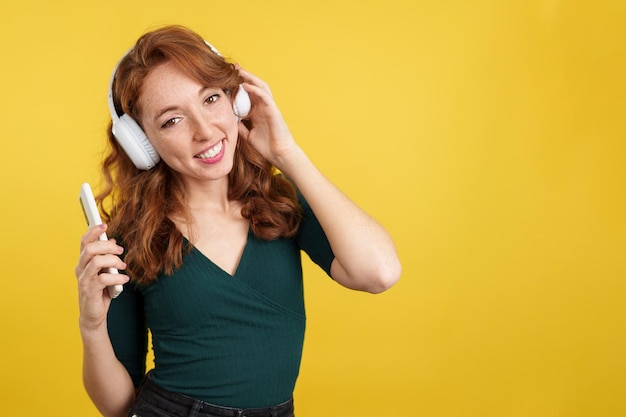 Redheaded woman listening to music and smiling at camera