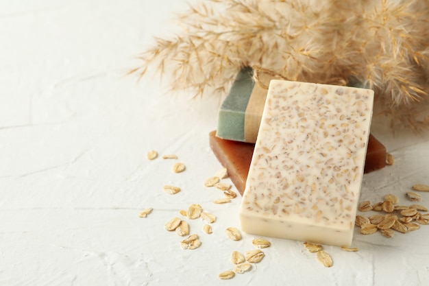 Reed branches and natural soap on white table