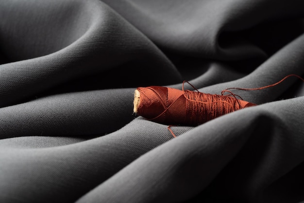 Reel with brown threads on gray silk fabric macro texture closeup Luxurious bright beautiful background for sewing Tailoring the concept of the atelier High fashion natural fabrics