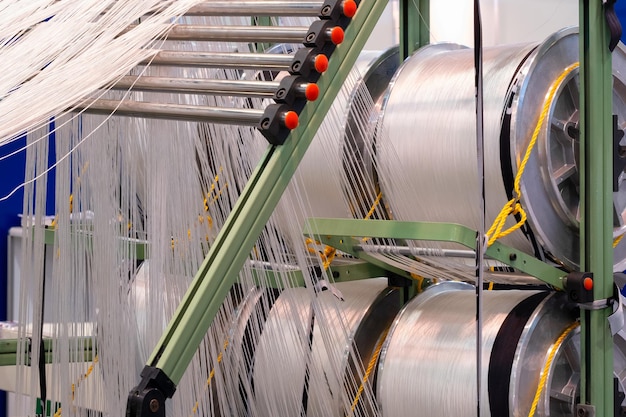 Reels of textile yarn thread at industrial weaving manufacturing machine