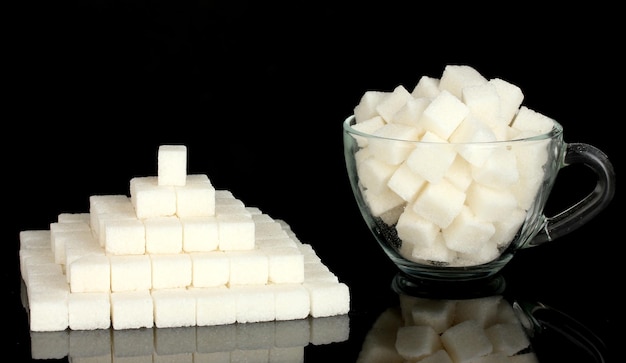 Refined sugar in glass cup isolated on black