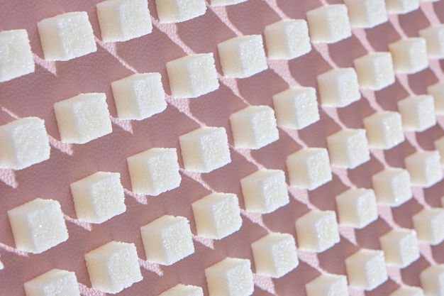 Refined sugar on pink background.Cubes of sweet and white sugar in geometricshape. Hard shadows.