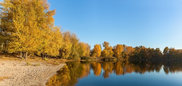 Reflection of autumn bright forest in the smooth surface of the river on a sunny day