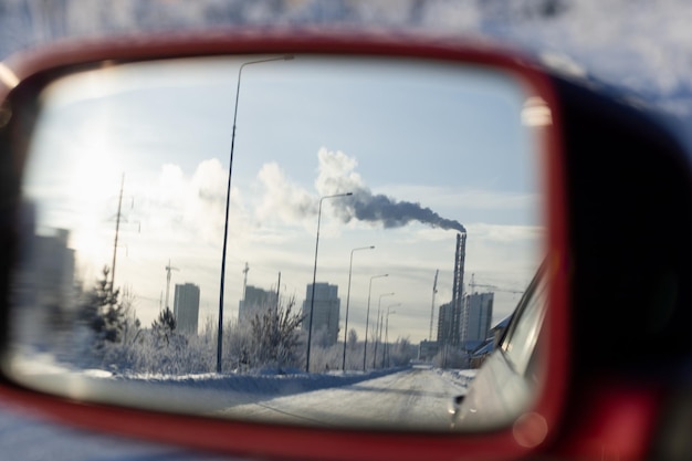 Reflection of the cityscape in the rearview mirror of the car on a frosty winter day