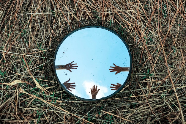 Reflection of hands in a mirror that lies on the grass