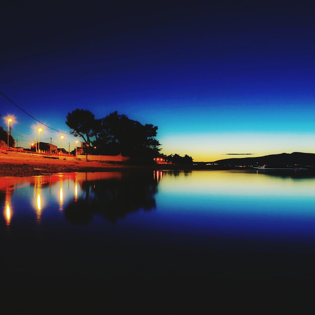 Photo reflection of silhouette trees in water at night