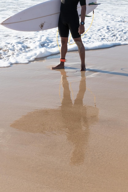 Reflection of a surfer on the beach shore