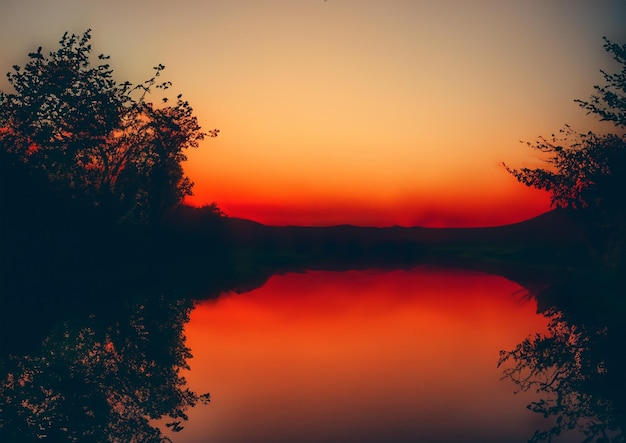 Reflection of trees and mountains on the lake at sunset