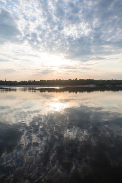 Reflection in the water of peaceful sunrise in the sunny morning on the Dnipro river Kyiv Harbour city Ukraine