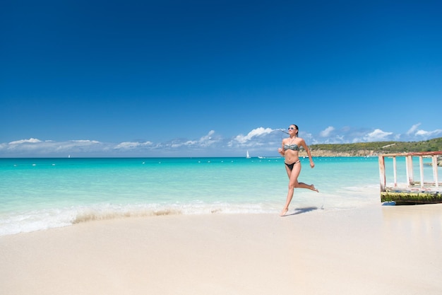 Refreshed and joyful Girl bikini run wave azure ocean beach Vacation luxury tropic ocean beach resort Woman sexy body relax ocean white sand beach Antigua Run through magical turquoise lagoon