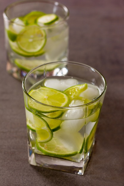 Refreshing cocktail with green lemon and ice close up